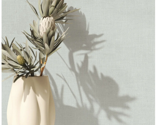 Gestructureerd behang met linnenlook op een muur met een vaas met droogbloemen en schaduwen.