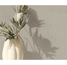 Vliesbehang met linnenstructuur in beige op een muur achter een vaas met protea-bloemen.