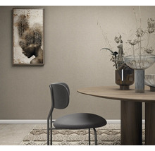 Behang met structuur in een modern ingerichte eetkamer met ronde houten tafel, moderne stoel en wanddecoratie.
