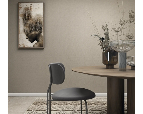 Behang met structuur in een modern ingerichte eetkamer met ronde houten tafel, moderne stoel en wanddecoratie.