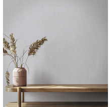 Vliesbehang met linnenlook op een muur achter een vaas met droogbloemen op een houten bank.