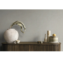 Behang met linnenstructuur op een muur achter een dressoir met decoratieve vazen en schalen.