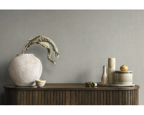 Behang met linnenstructuur op een muur achter een dressoir met decoratieve vazen en schalen.