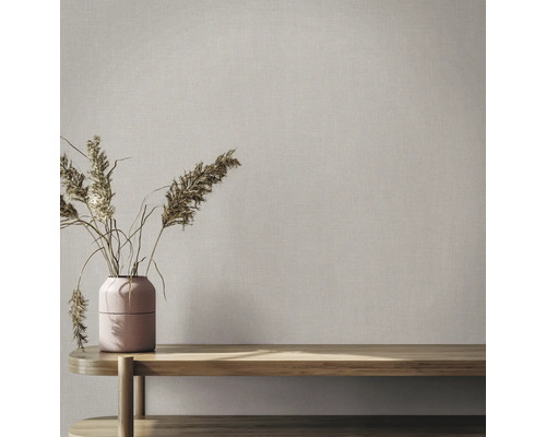 Behang met linnenstructuur in een lichte kamer met houten bank en vaas met droogbloemen.