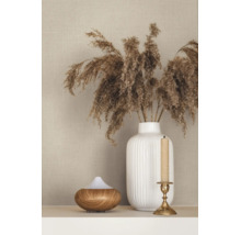 Beige behang met linnenstructuur achter een witte geribbelde vaas met drooggras, een aroma diffuser en een kandelaar.