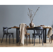Lichte, moderne eetkamer met gestructureerd behang op de muur, een houten tafel met metalen poten en verschillende stoelen.
