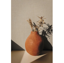 Decoratieve terracotta vaas met gedroogde planten en een tarweaar voor een gestructureerde wand.