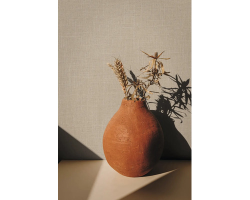 Decoratieve terracotta vaas met gedroogde planten en een tarweaar voor een gestructureerde wand.