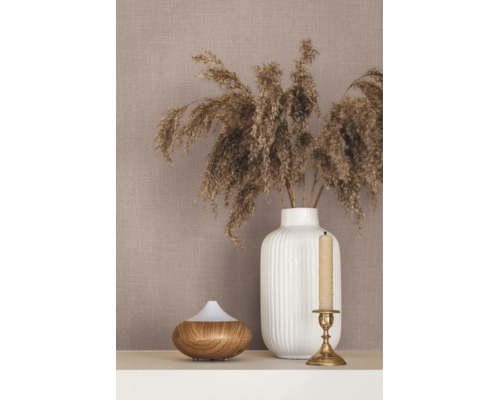 Behang met linnenstructuur, gedecoreerd met een witte geribbelde vaas met drooggras, een aroma diffuser met houtlook en een kandelaar.
