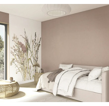 Lichte slaapkamer met wit bed, fotobehang met bloemen, een oudroze muur, bijzettafels van rotan en een ronde geplooide plafondlamp.