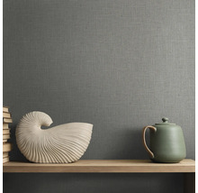 Behang met linnenstructuur in een kamer met een houten plank, een schelpvormig beeldje en een theepot.