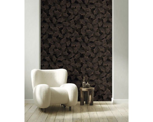 Vliesbehang met ginkgobladmotief in een lichte woonkamer met witte fauteuil en houten tafel.
