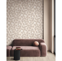 Moderne woonkamer met behang met ginkgobladpatroon, een mauve fluwelen bank en een zwarte bijzettafel op een lichte parketvloer.