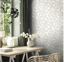 Licht interieur met ginkgo-behang, een houten bureau met orchideeën in een vaas en hangplanten bij het raam.