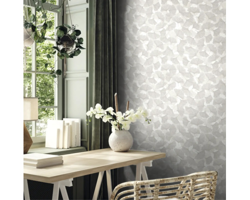 Licht interieur met ginkgo-behang, een houten bureau met orchideeën in een vaas en hangplanten bij het raam.
