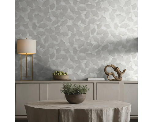 Behang met ginkgobladpatroon in een lichte, georganiseerde woonkamer met dressoir, tafellamp en decoratieve elementen.