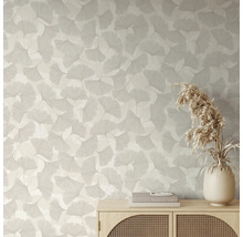 Behang met ginkgobladpatroon in een lichte kamer achter een houten dressoir met vaas en droogbloemen.