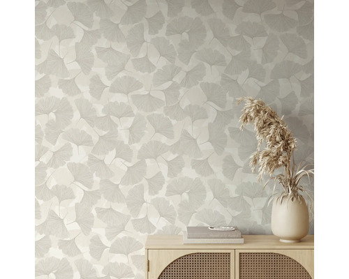 Behang met ginkgobladpatroon in een lichte kamer achter een houten dressoir met vaas en droogbloemen.