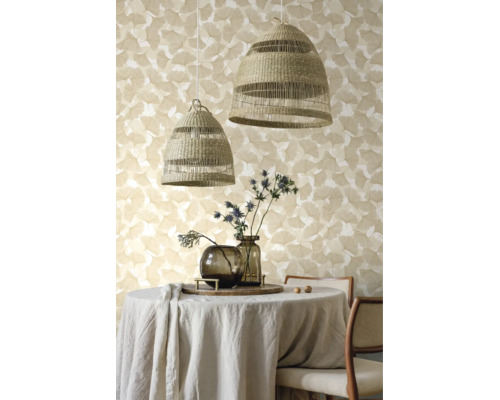 Behang met ginkgopatroon achter een ronde eettafel met linnen tafelkleed, twee gevlochten hanglampen en glazen vazen met distels.