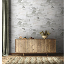 Vliesbehang met een landschapspatroon van heuvels en bomen achter een houten dressoir in een natuurlijk ingerichte kamer.