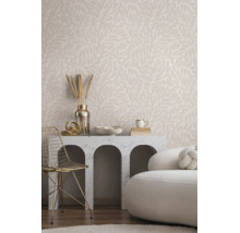 Lichte woonkamer met vliesbehang met bladmotief, marmeren consoletafel met bogen, gouden metalen stoel en witte bank.