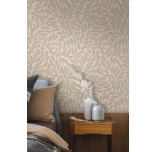 Behang met bladmotief in een slaapkamer boven een nachtkastje met vazen en droogbloemen naast een bed.