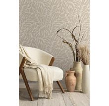 Vliesbehang met bladmotief in een lichte kamer met fauteuil, deken en decoratieve vazen met droogbloemen.