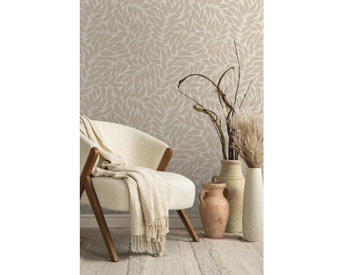 Vliesbehang met bladmotief in een lichte kamer met fauteuil, deken en decoratieve vazen met droogbloemen.