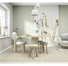 Lichte eetkamer met vliesbehang met grassen en distels, een ronde houten tafel en houten zitmeubels op een vloerkleed.
