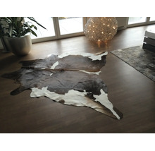 Koeienhuid vloerkleed van echt leer in een modern ingerichte woonkamer met houten vloer.
