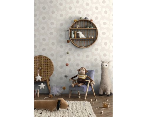 Kinderkamer met behang met groot bloemenpatroon, een ronde rotan wandplank en knuffels in een lichte, speelse Boho-stijl