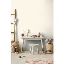 Licht ingerichte kinderkamer met behang met patroon, wit bureau en kruk met houten poten, manden en speelgoed.