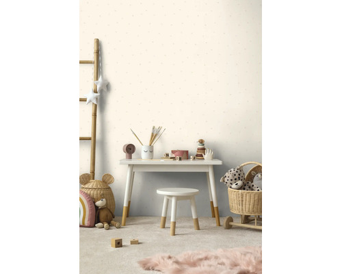 Licht ingerichte kinderkamer met behang met patroon, wit bureau en kruk met houten poten, manden en speelgoed.
