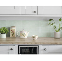 Licht ingerichte keuken met lichtgroene mozaïek tegels als achterwand, werkblad in houtlook en witte kasten.