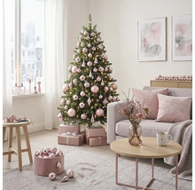 Lichte woonkamer met versierde kerstboom, roze kerstballen, cadeaus, grijze bank met kussens en een salontafel.