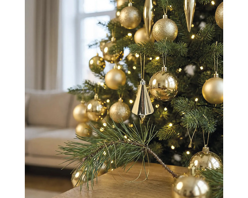 Kerstboom gedecoreerd met gouden ballen en kegels, verlicht met warmwitte LED-verlichting in een woonkamer.
