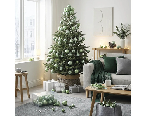 Licht ingerichte woonkamer met versierde kerstboom in rieten mand, bank en houten salontafel met kerstballen en cadeaus.