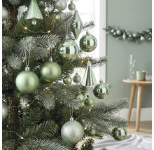 Kerstboom versierd met matte, glanzende en glitterende ballen, druppelvormige ornamenten en een led-lichtsnoer in een lichte omgeving.