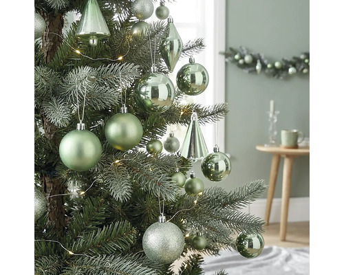 Kerstboom versierd met matte, glanzende en glitterende ballen, druppelvormige ornamenten en een led-lichtsnoer in een lichte omgeving.