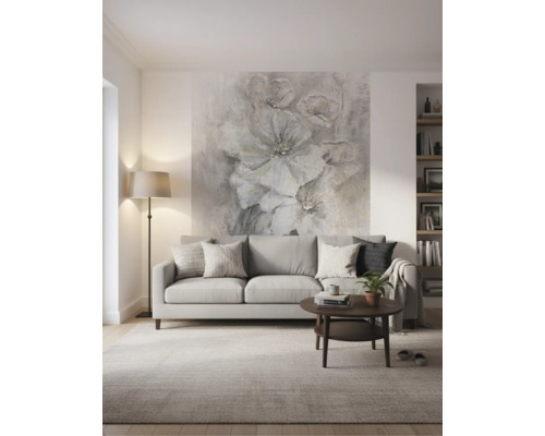 Moderne, lichte woonkamer met een grijze bank, donkere salontafel en een groot fotobehang met bloemen aan de wand achter de bank.