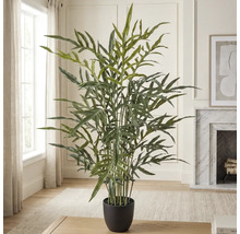 Grote kunstpalm in zwarte pot in een lichte, modern ingerichte woonkamer met open haard.
