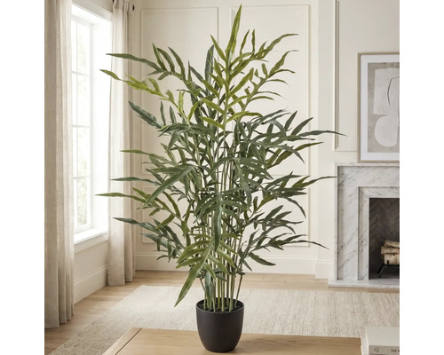 Grote kunstpalm in zwarte pot in een lichte, modern ingerichte woonkamer met open haard.