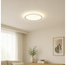 Platte, ronde LED-plafondlamp in een lichte, minimalistische woonkamer met houten meubels en decoratie.