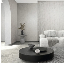 Moderne woonkamer met vliesbehang met patroon, gestructureerde wand, bank en ronde salontafel in een licht, minimalistisch ontwerp.