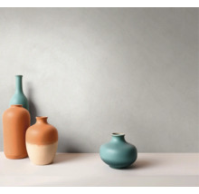 Vier keramische vazen in verschillende vormen en maten voor een gestructureerde muur in een minimalistische, lichte omgeving.