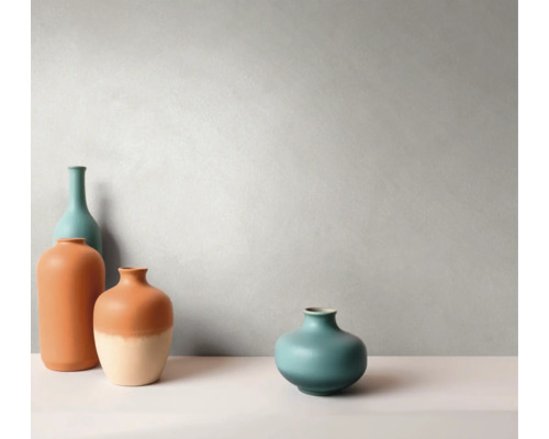 Vier keramische vazen in verschillende vormen en maten voor een gestructureerde muur in een minimalistische, lichte omgeving.