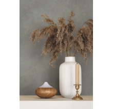 Decoratieve opstelling met een witte geribbelde keramische vaas, gedroogd pampasgras, een diffuser in houtoptiek en een kandelaar voor een wand met textuur.