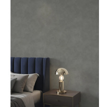 Slaapkamer met een donkergrijze muur met textuur, een blauw fluwelen hoofdbord en een goudkleurige tafellamp op een nachtkastje.