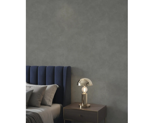 Slaapkamer met een donkergrijze muur met textuur, een blauw fluwelen hoofdbord en een goudkleurige tafellamp op een nachtkastje.