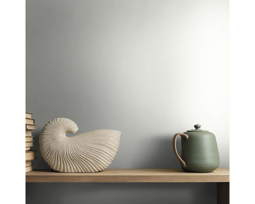 Houten plank met een schelpvormige keramische decoratie, een groene theepot en een stapel boeken in een lichte, minimalistische stijl.